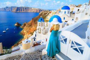 Blond-woman-on-the-streets-of-Santorini-looking-at-sea-cm