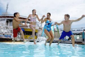 Parents with children (10-12) jumping into pool on cruise ship-cm
